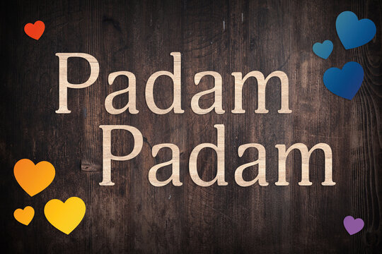 Padam Padam with rainbow hearts on dark wooden board