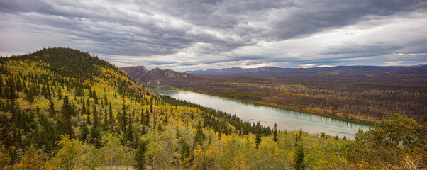 Landscape with Yukon river in autumn colors under overcast sky, Yukon territory Canada - obrazy, fototapety, plakaty
