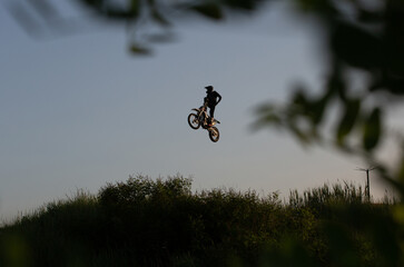 FMX rider performs dangerous stunts at sunset. Motocross.