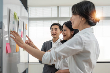 Casual creative happy two smile asian business people plan strategy analysis and brainstorm putting post it sticker note to share idea for startup project on white board at modern office