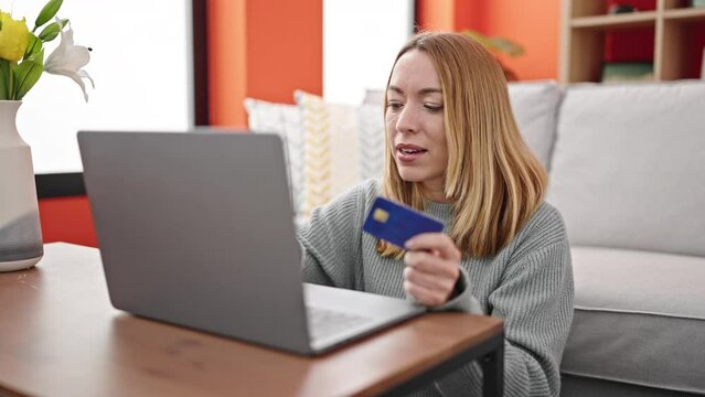 Young blonde woman shopping with laptop and credit card with winner expression at home