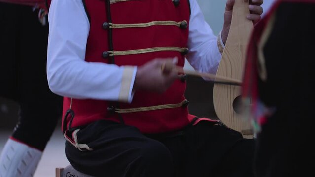 A musician plays Balkan violin surrounded by dancers, in Bosnia