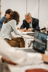 Mature businessman giving tips and tricks to his young colleagues for better work efficiency