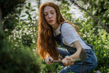 Ginger girl digging in garden. She is about to plan flowers
