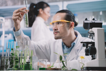Fototapeta premium Researcher men are looking to simple reefs in tube on his hands and research women are hold a simple tube on behind researcher men at cosmetic lab and laboratory