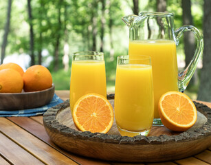 Orange juice in glasses and pitcher with sliced oranges