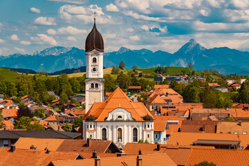 Alpine summer view with a church and the alps in the background at Nesselwang, Ostallgaeu, Bavaria,...