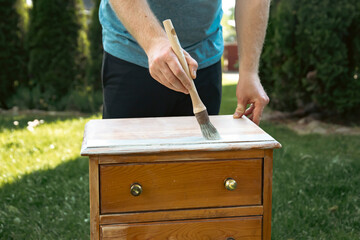 Painting a wooden furniture outdoors, an eco-friendly re-use business.