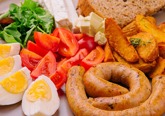 sausages with boiled eggs, tomatoes and potatoes with cheese