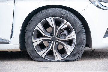 Close-up of flat right front wheel of car standing on road with alloy disc. Forced emergency stop...
