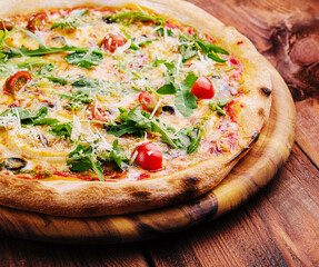 Pizza with arugula, cheese, yoghurt and cherry tomatoes closeup