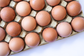 Fresh chicken brown eggs in a tray on a white background. View from above.