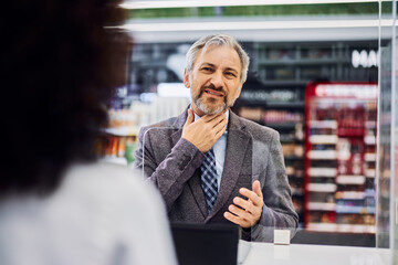 A senior businessman complains of a sore throat and asks for medicine in a drugstore.