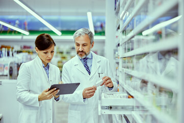 A female and male pharmacist looking at the tablet while doing inventory.
