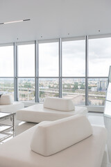 Fototapeta na wymiar a white and very bright luxury fashionable apartment on a high floor with a free layout, a living room with expensive furniture and panoramic glazing