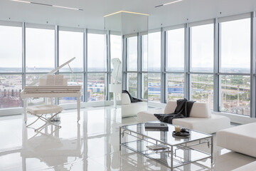 a white and very bright luxury fashionable apartment on a high floor with a free layout, a living room with expensive furniture and panoramic glazing