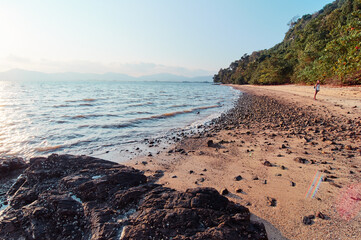 Beach with sand, rocks, stones and blue sky.