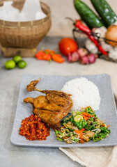 Bebek Goreng Lalapan or Fried duck, One of Indonesia's culinary icons on decorated background with rice and vegetables