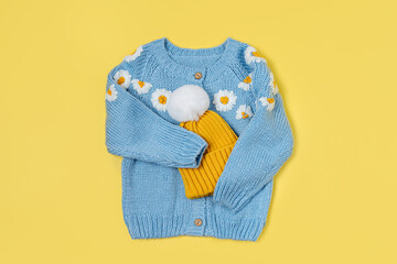 Cute blue knitted children's jacket with yellow hat. Stylish kids clothes for spring, autumn or winter. Fashion outfit. Flat lay, top view