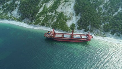 Aerial view of abandoned cargo ship. Bulk carrier ran aground after the storm. Dry cargo ship stands ashore.