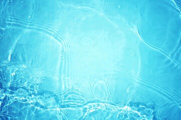 Blue water with ripples on the surface. Defocus blurred transparent blue colored clear calm water surface texture with splashes and bubbles. Water waves with shining pattern texture background.