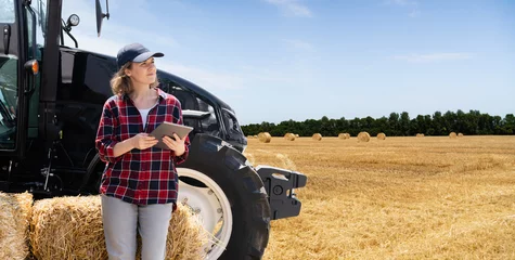 Cercles muraux Tracteur Woman farmer with a digital tablet next to agricultural tractor