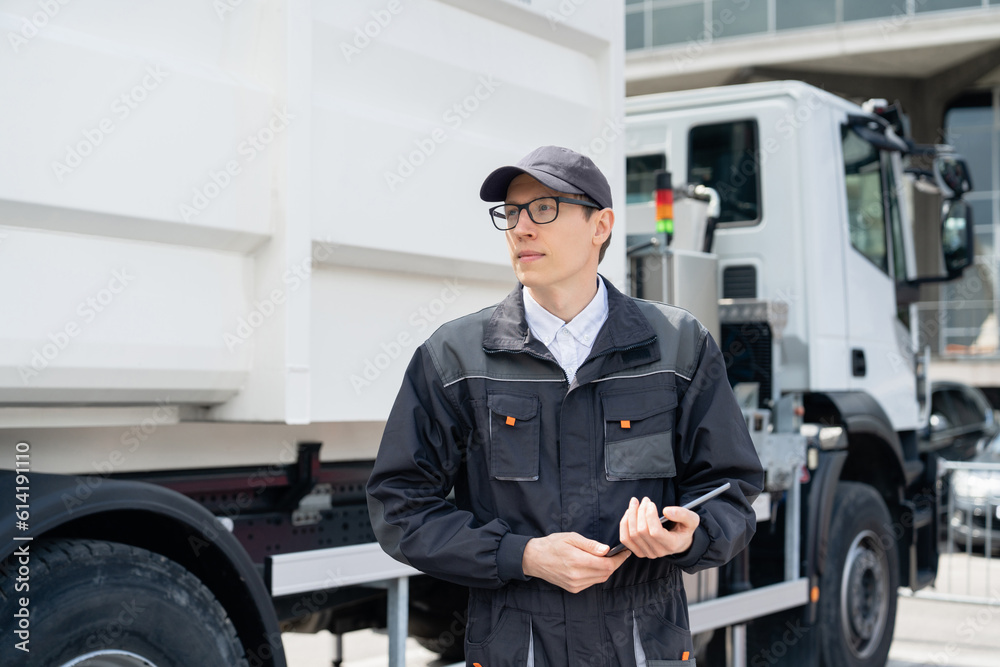 Poster manager with a digital tablet next to garbage truck..