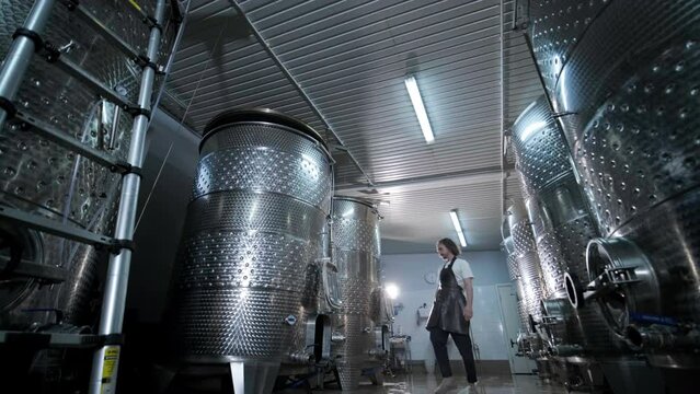 Authentic shot of successful male sommelier is tasting a flavor and checking white wine quality poured in transparent glass in a wine cellar.