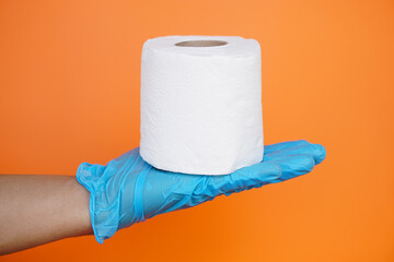 Close up hand holds roll of white tissue paper, isolated on orange background. Concept, cleaning tool, hygienic to wipe dirty and absorb wet ,use tissue paper for hygienic and sanitary.Toilet paper 