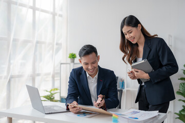 Two Young Asian business people discuss with new startup project Idea presentation, analyze planning and financial statistics and investment market at office.