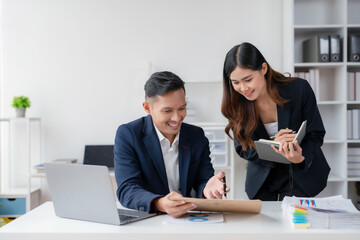 Two Young Asian business people discuss with new startup project Idea presentation, analyze planning and financial statistics and investment market at office.