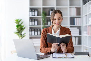 Fototapeta na wymiar Beautiful young business woman manager or company worker holding accounting document, checking financial data or marketing report working in office with laptop. Accountant consults on some document.