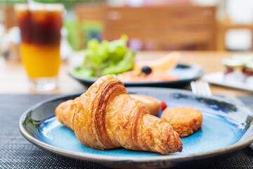Continental breakfast served on table. Butter Croissant and smoked salmon with iced fresh orange juice topped with espresso on wooden table in a garden, make a good day.