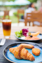 Continental breakfast served on table. Butter Croissant and smoked salmon with iced fresh orange juice topped with espresso on wooden table in a garden, make a good day.