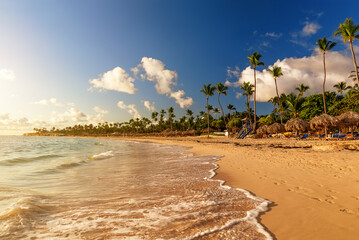 Coconut palm trees on white sandy beach against colorful sunset in Punta Cana, Dominican Republic.