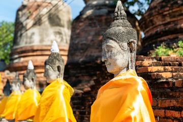 Aligned Buddha statues at Wat Yai Chai Mongkol (or Mongkhon), Ayutthaya, Thailand. - obrazy, fototapety, plakaty