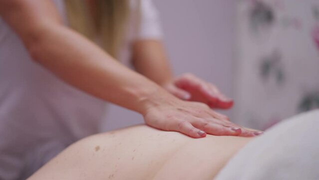 Close-up masseuse female hands massaging person's back, applying pressure to skin, providing stress relief, wellbeing, and body health