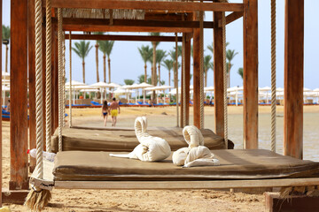 Swing in a beach bungalow on seacoast with towels in swan shape. Summer vacation and relax on sea...