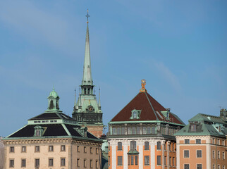 Obraz premium Clock tower of the German church and old houses in the old town Gamla Stan, a sunny summer morning in Stockholm