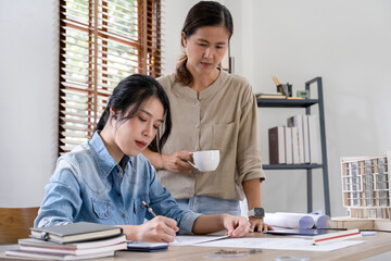 Obraz premium Engineers discuss a blueprint while checking information on a tablet computer in a office.