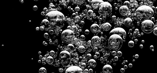 Soda water bubbles splashing underwater against black background. Cola liquid texture that fizzing...