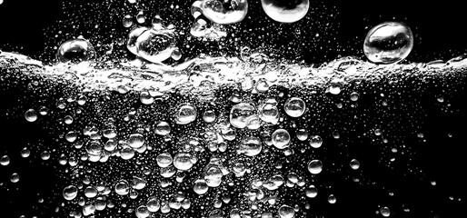 Soda water bubbles splashing underwater against black background. Cola liquid texture that fizzing...