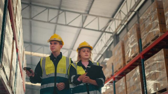 Man and woman workers checks products stock inventory with digital tablet in the retail warehouse full of shelves, Workers employee wearing hard hat doing work in storehouse.	