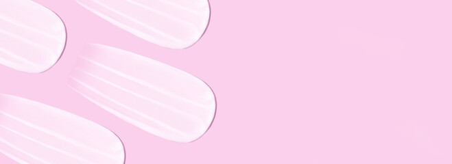 The background is cosmetic. Many smears of cream on a pink purple background