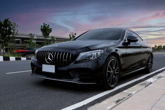 luxury black color Mercedes Benz sports car,  c class c200 coupe AMG model park on the road in the evening near train station during a long road trip with background of beautiful twilight sky