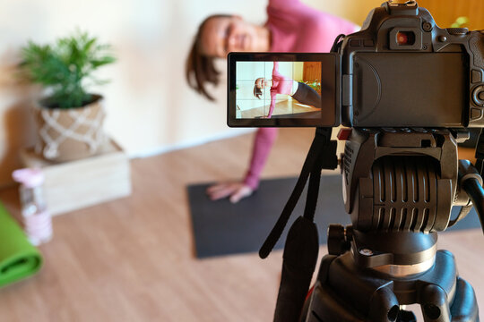 Sports online vlogging, fitness coach recording workout course using video camera for internet streaming.