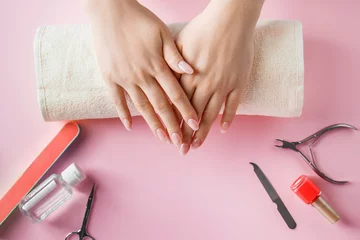 Photo sur Plexiglas Spa Nail care procedure in a beauty salon. Female hands and tools for manicure on pink background. Concept spa bodycare.