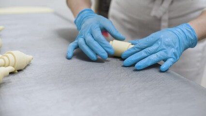 Making croissants. Women's hands twist classic croissants in the bakery shop. Production of bakery products