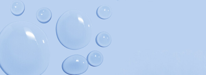 large drops of cosmetic serum, liquid, water, gel on a pink background