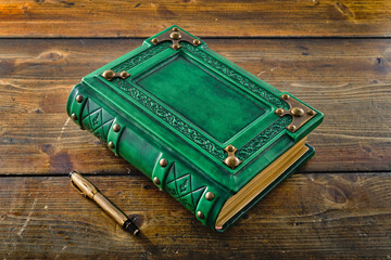 Green leather book with metal corners captured on wooden table